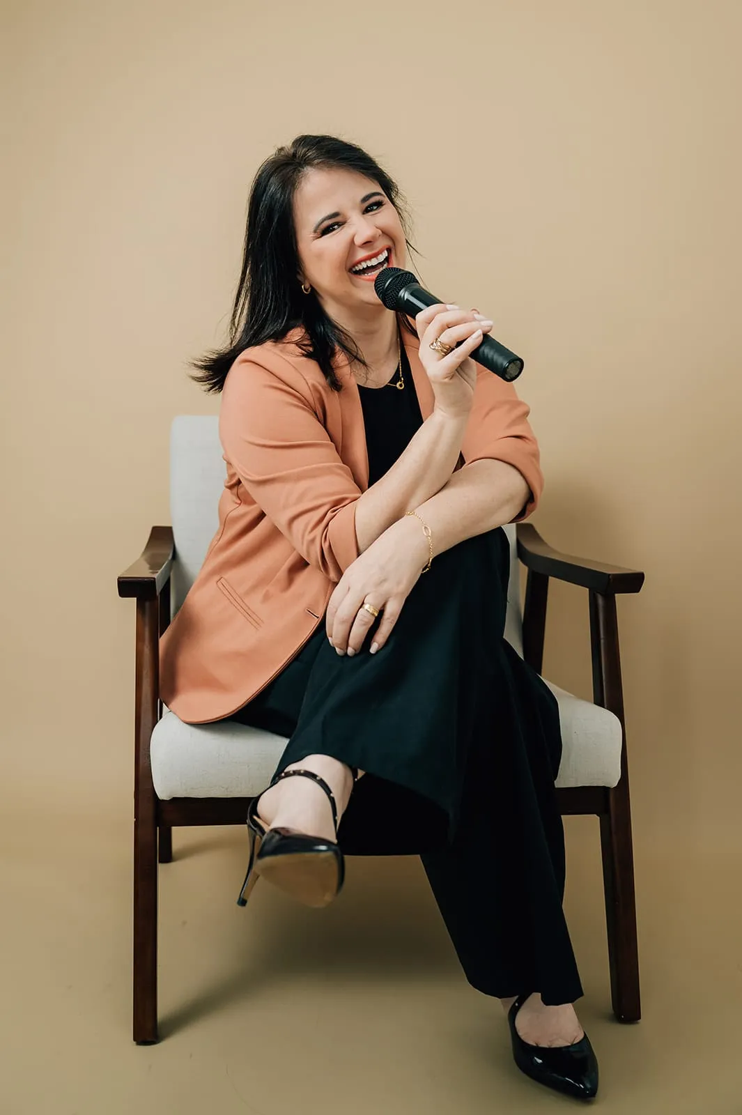 Luísa Marteleto sorrindo, sentada com microfone