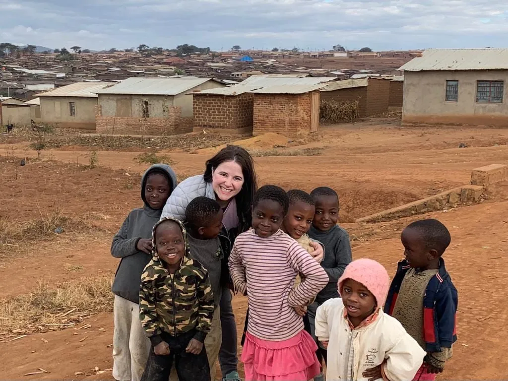 Luísa Marteleto with children in front of homes in the community